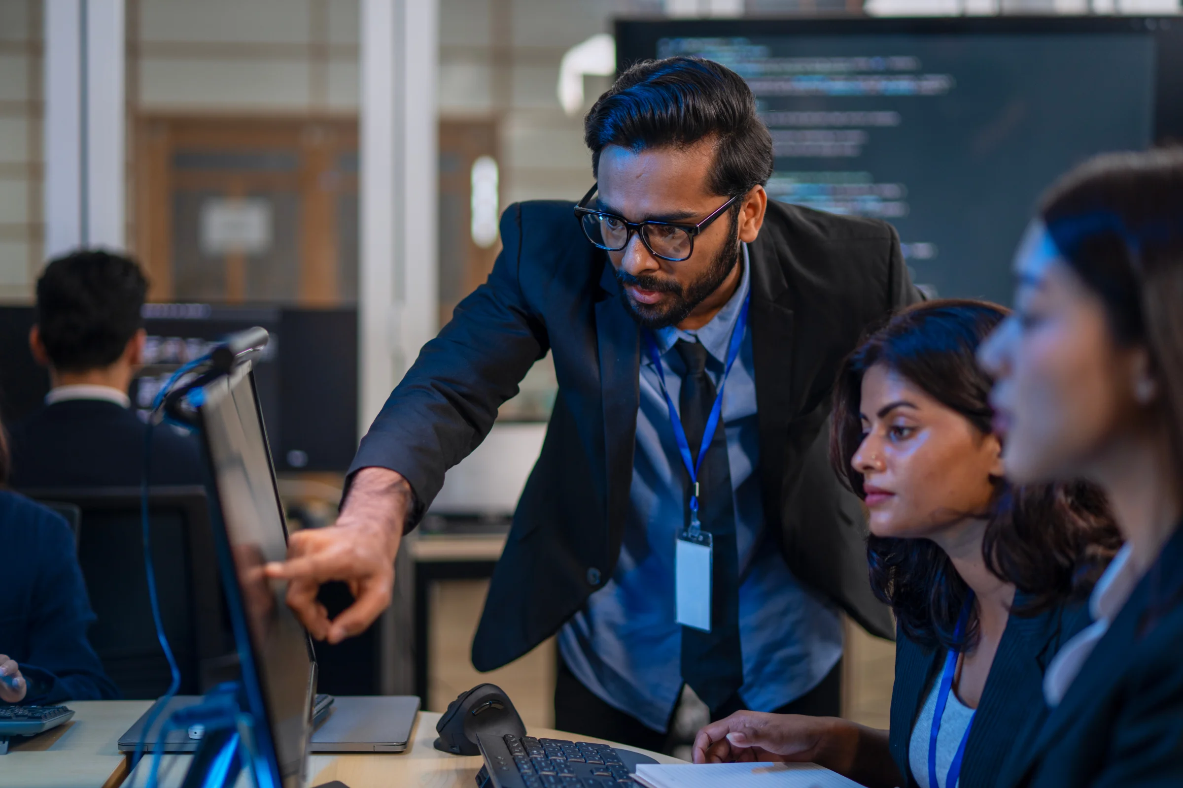 Technology colleagues reviewing work at computer screens.