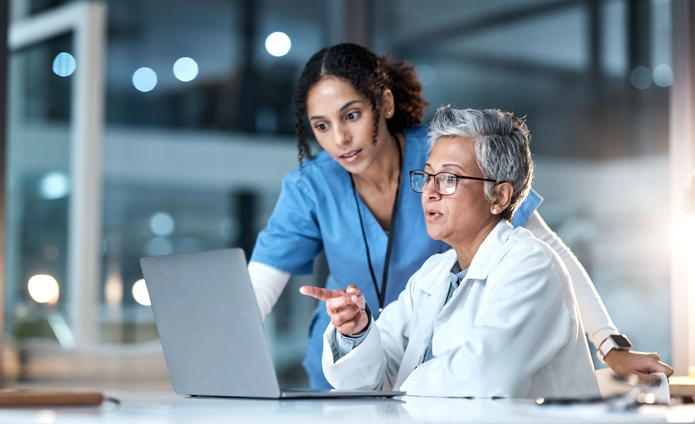 Two healthcare professionals reviewing a laptop.