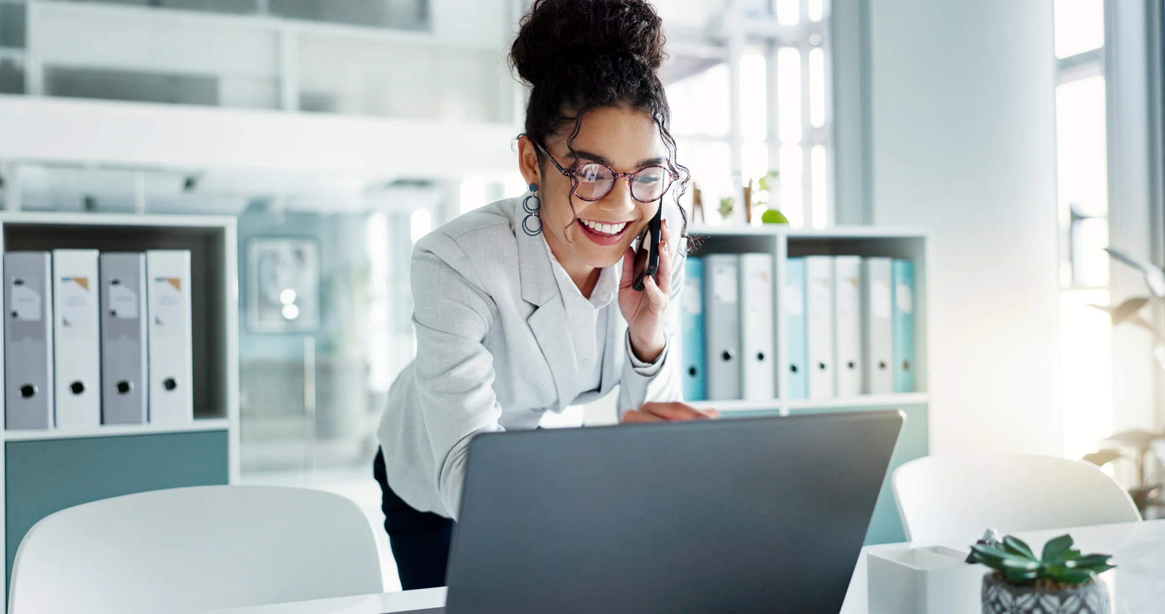 Professional using a laptop while talking on the phone.
