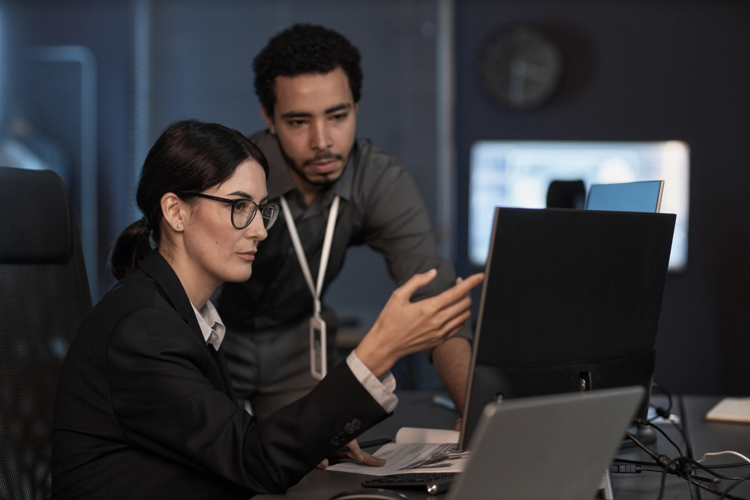 Two colleagues reviewing information on computer monitors.