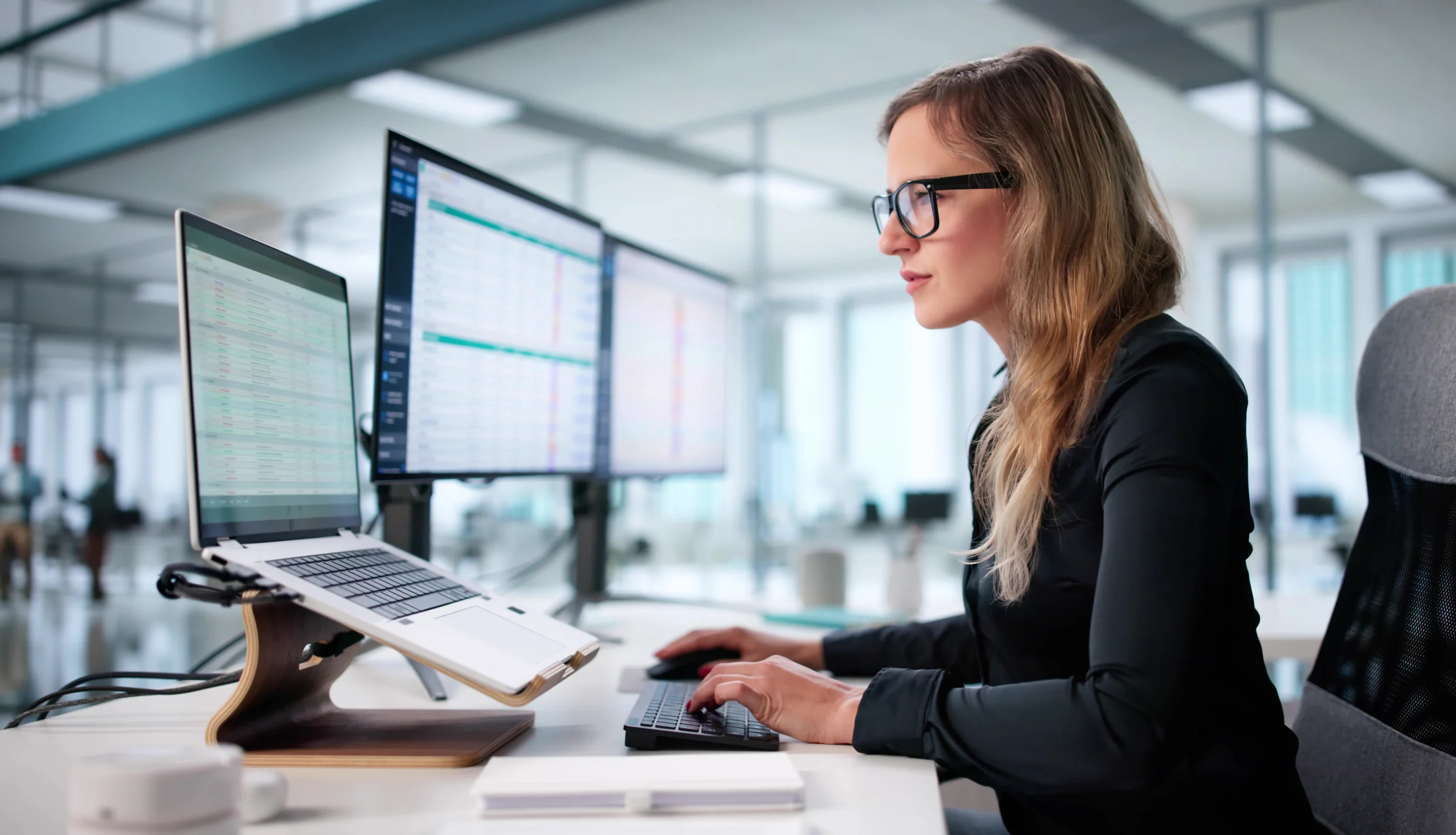 Technology professional working with a laptop and multiple monitors.